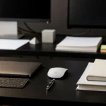 Organized desk workspace with laptop, keyboard, mouse, notebooks, and monitors with sticky notes.