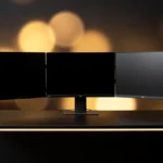 Multiple computer monitors and laptops arranged on desks with warm backlighting.